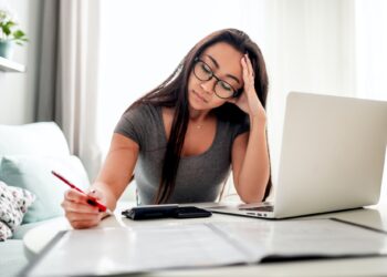 Desperate and worried asian woman calculating taxes bills at home