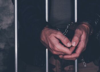 Handcuffed man behind prison bars